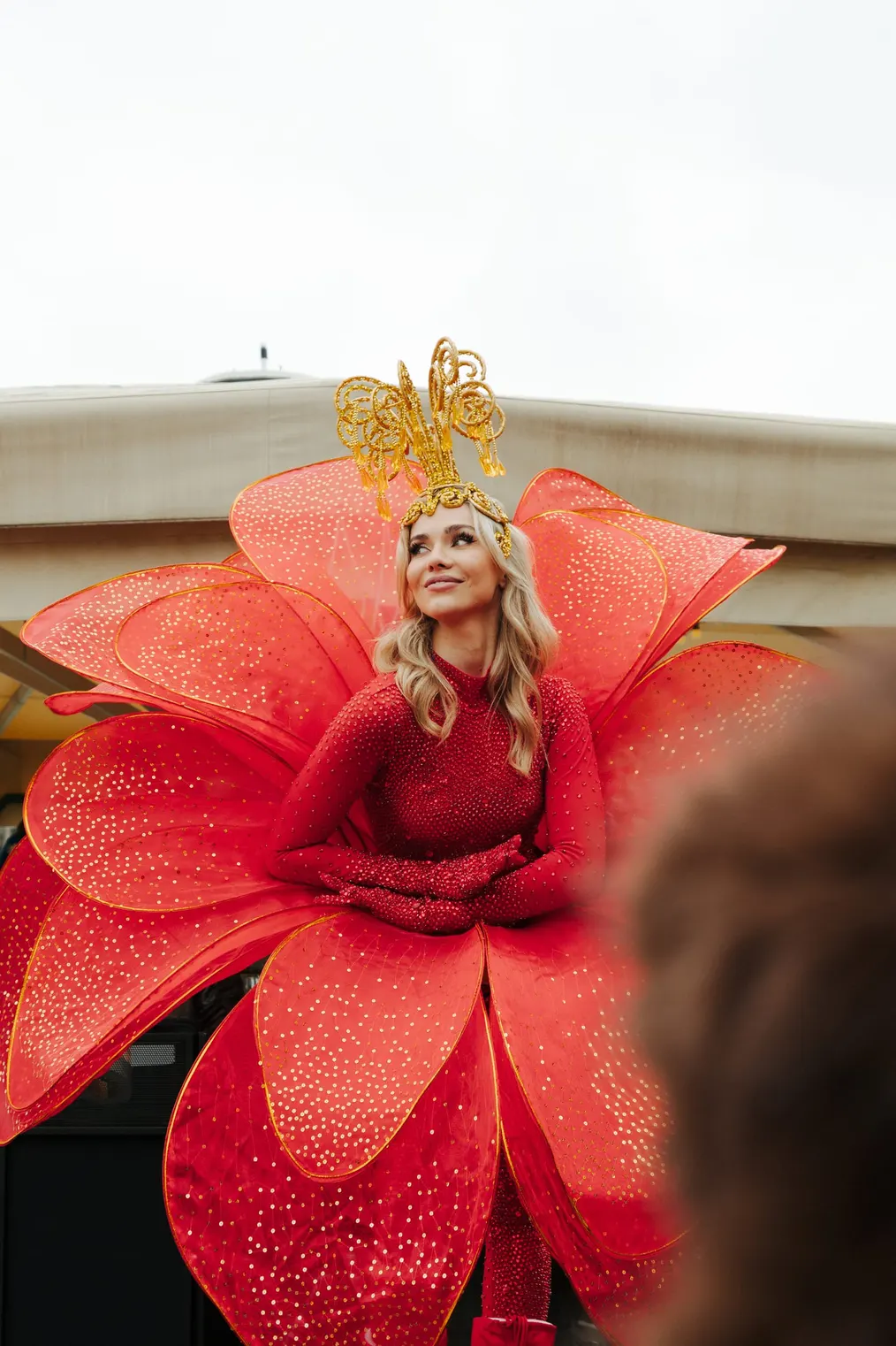 Performerin im Blütenkostüm mit goldener Krone